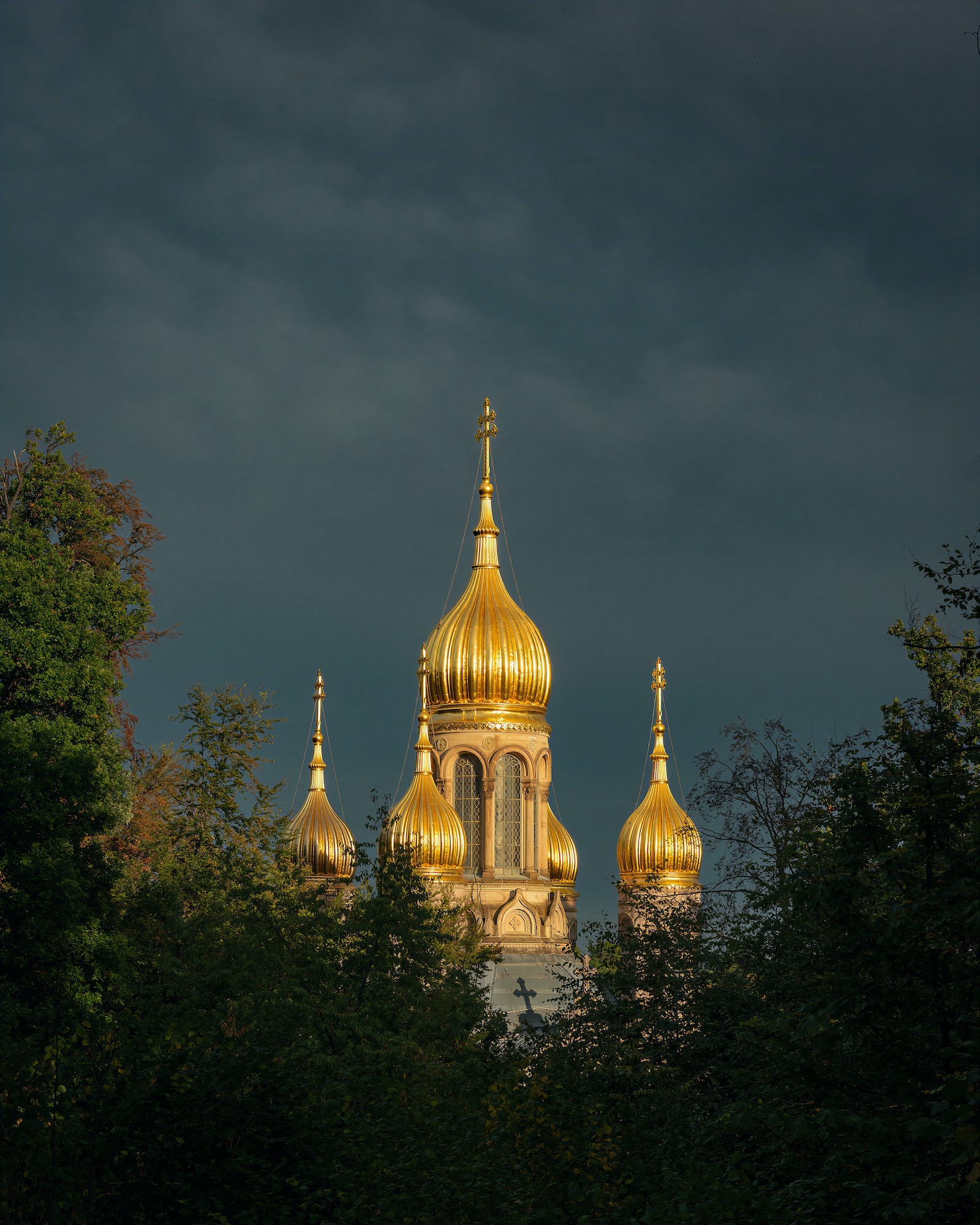 Golden domes of the Russian church in Wiesbaden against a dark, stormy sky